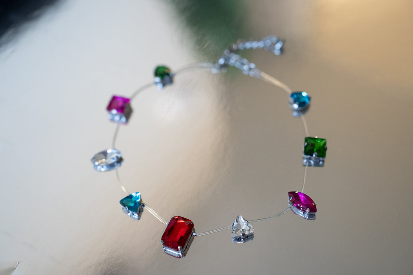 Necklace with colorful gemstones on a reflective surface