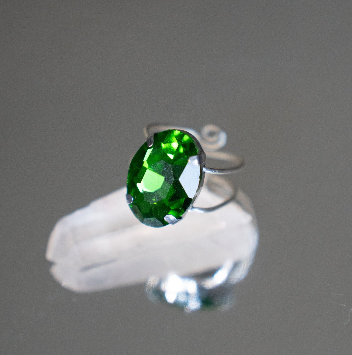Silver ring with a green gemstone on a gray background