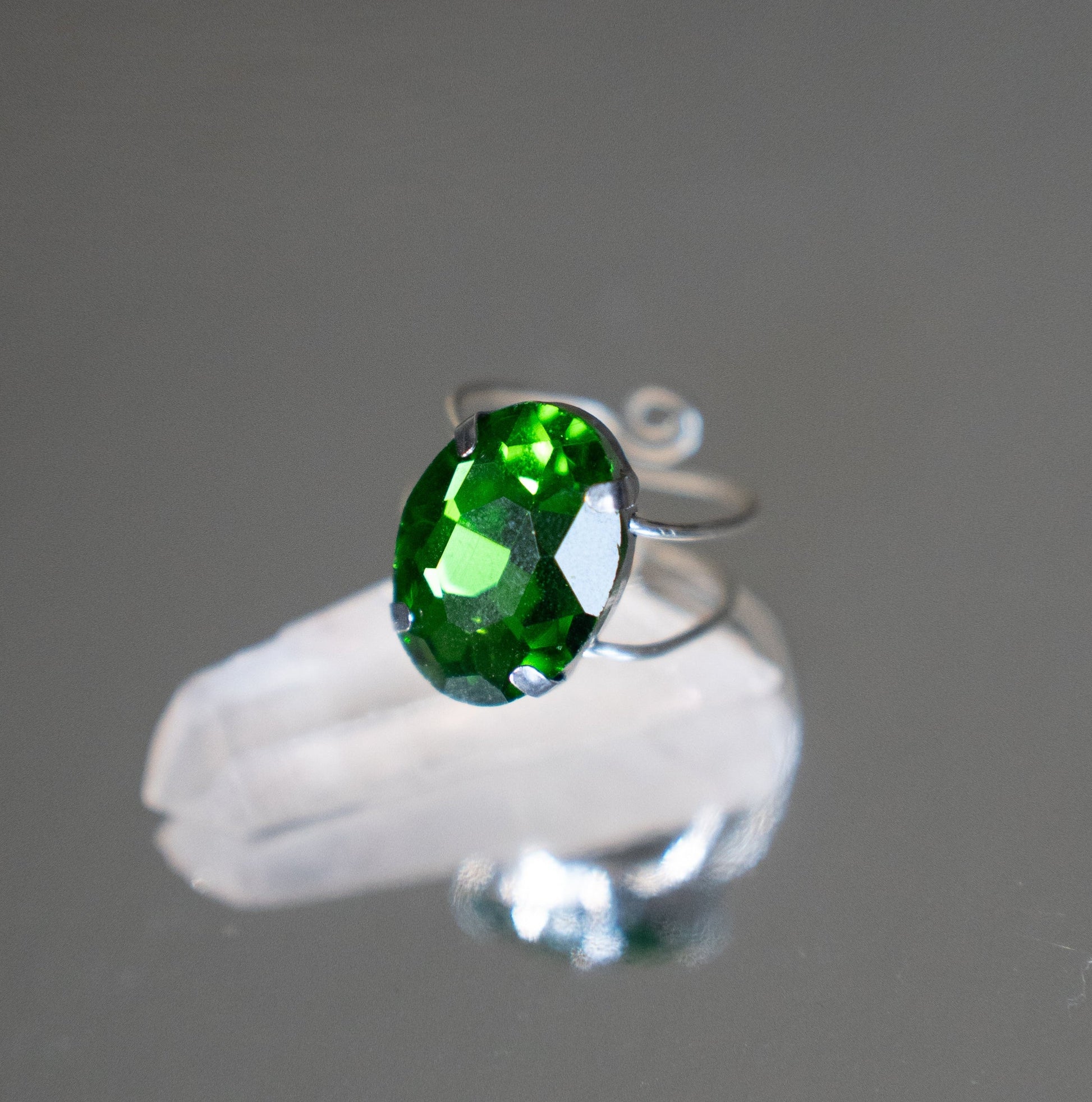 Silver ring with a green gemstone on a gray background
