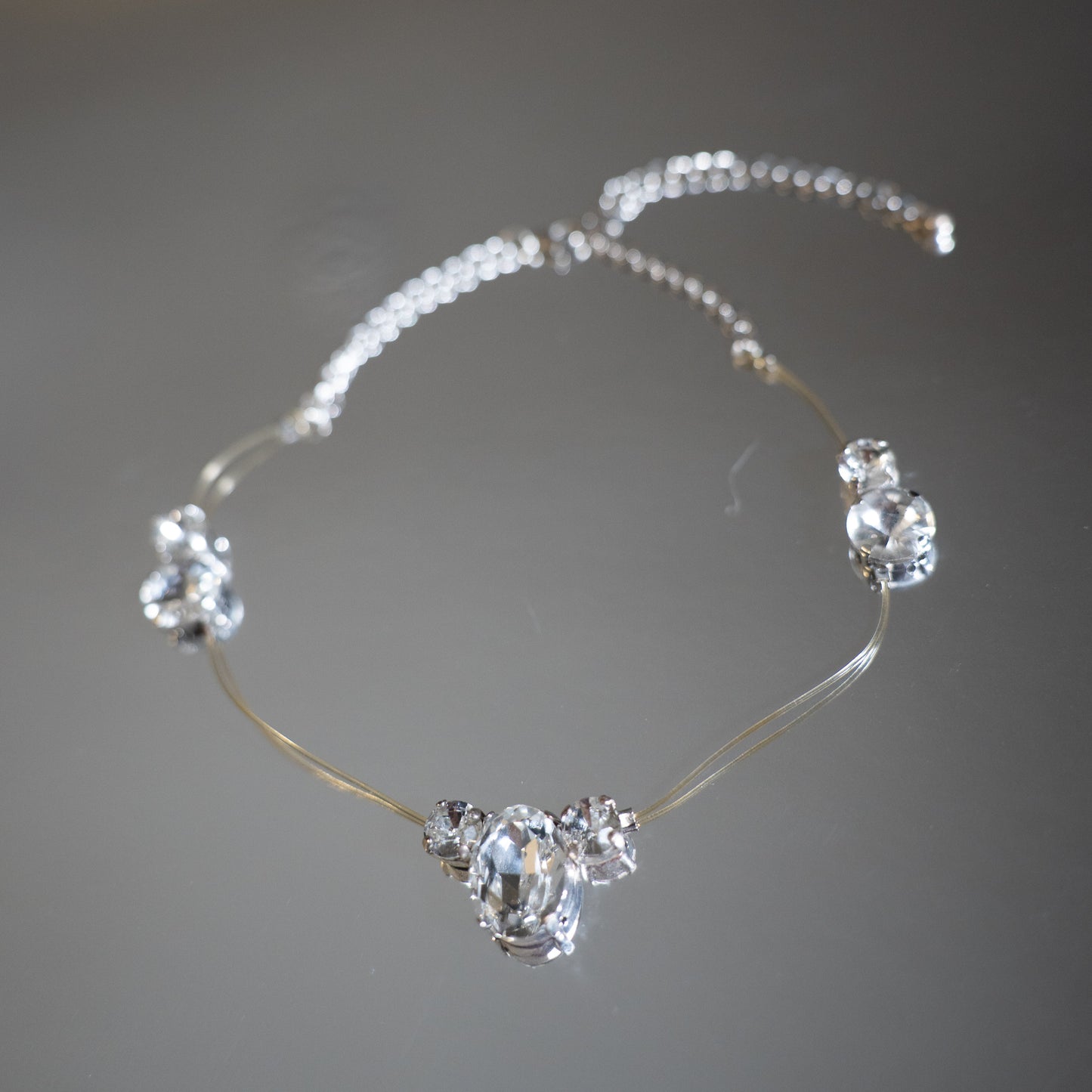 Silver necklace with clear gemstones on a blurred background