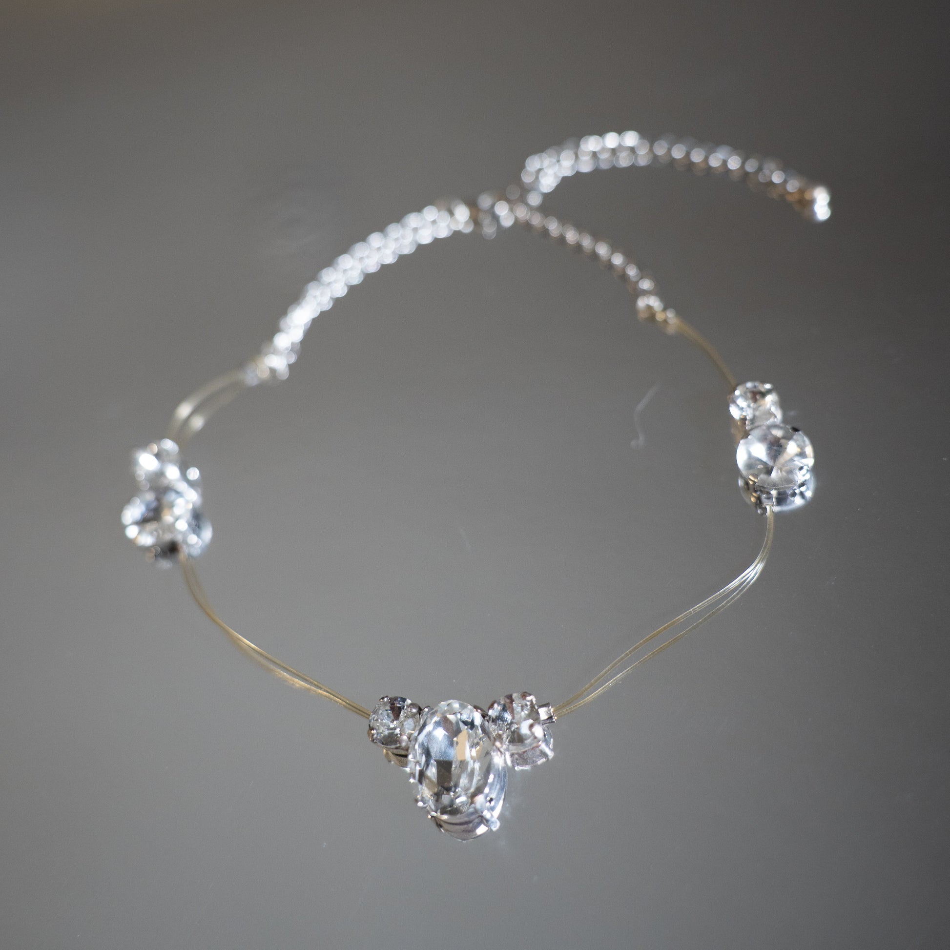 Silver necklace with clear gemstones on a blurred background
