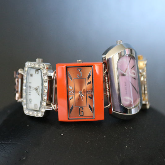 Three decorative watches on a black surface with a dark background