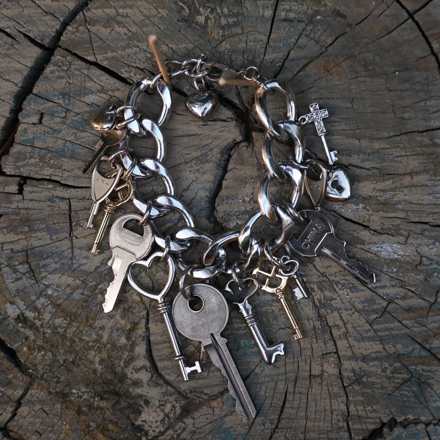 Silver key bracelet with various charms on a wooden surface
