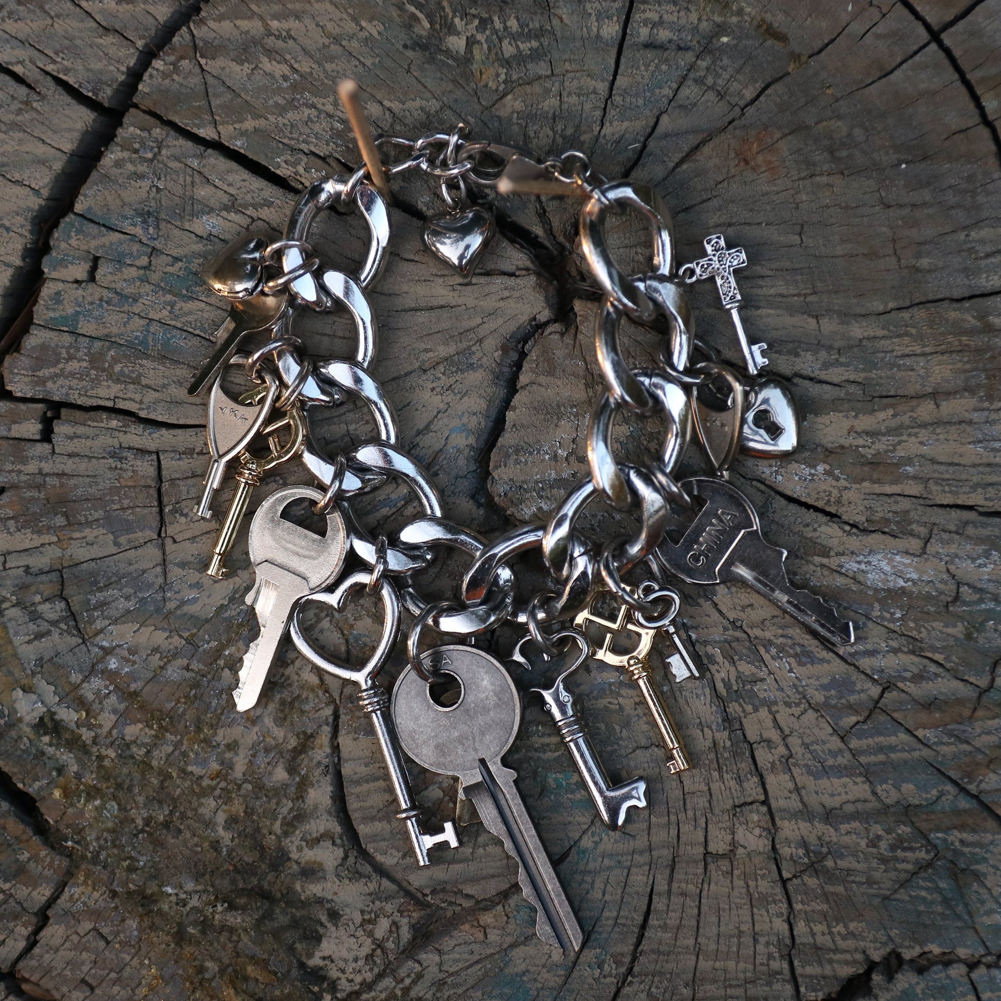 Silver key bracelet with various charms on a wooden surface