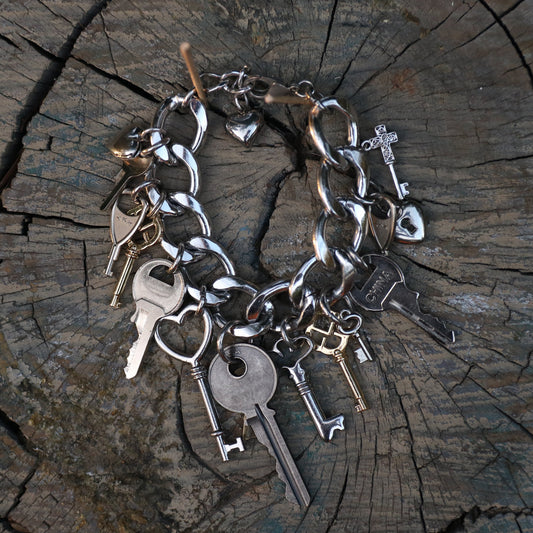 Silver key bracelet with various charms on a wooden surface