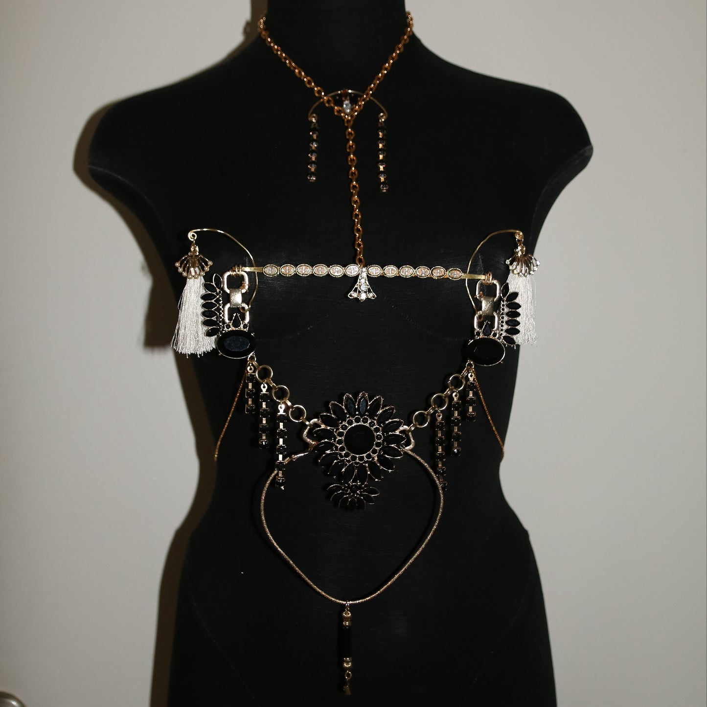 Jewelry set on a black mannequin bust against a plain background